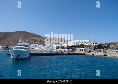 Die Yacht liegt im griechischen Inselhafen Folegandros. Kreuzfahrt-Motorboot vor Anker am Karavostasi Dock, weiße Gebäude und blauer Himmel Hintergrund. Sommerurlaub Stockfoto