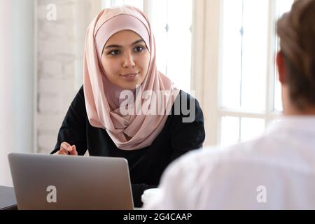 Schöne asiatische muslimische Geschäftsfrau im Gespräch mit Kollegen bei der Sitzung Stockfoto