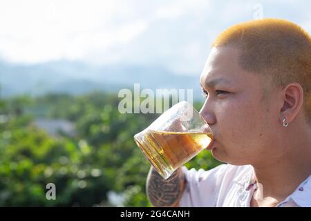 Ein junger Mann trinkt Bier, um seinen Urlaub zu feiern. Stockfoto