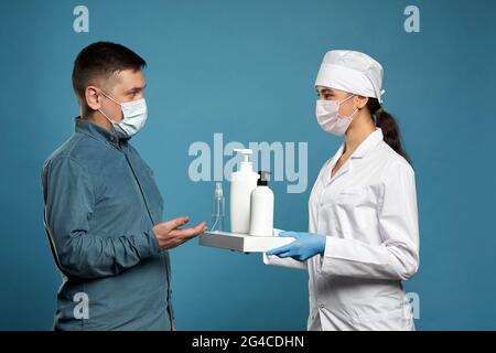 Arzt Anwendung antibakteriellen Spray auf Patienten Hände auf blauem Hintergrund Stockfoto