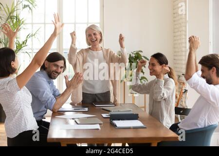 Begeistert verschiedene Mitarbeiter, deren Führungskraft mittleren Alters Erfolg feierte Stockfoto