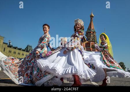 Moskau, Russland. 20. Juni 2021 Junge Frauen tanzen auf dem Roten Platz vor dem Hintergrund der Basilius-Kathedrale in russischen Nationalkostümen während des Buchfestivals „Roter Platz“ in Moskau, Russland Stockfoto