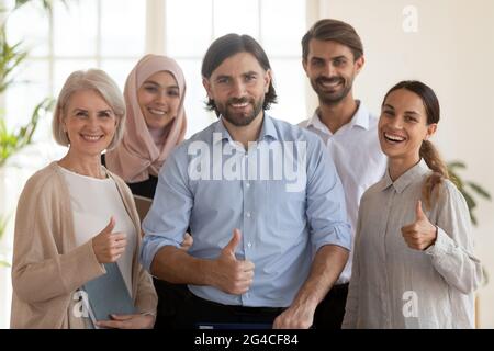 Gruppenportrait mit lächelnden Kollegen von multiethnischen Mitarbeitern, die den Daumen nach oben zeigen Stockfoto