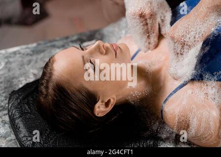 Nahaufnahme-Schaum-Peeling-Massage für Model im Spa. Entspannung im türkischen Hamam. Stockfoto