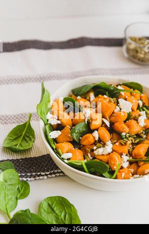 Kürbis-Gnocchi-Salat mit Feta-Käse und Baby-Spinatblättern mit weißem Hintergrund. Vegetarischer Salat, Mittagsrezept, einfaches Kochen Stockfoto