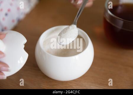 Nahaufnahme Frau, die einen Löffel Zucker in schwarzen Tee legt Stockfoto