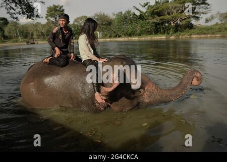 Ein Mahout und ein freiwilliger Arbeiter reiten auf einem Elefanten, nachdem er ihn im Sumatran Elephant Rehabilitation Center im Way Kambas National Park, Indonesien, gebadet hat. Stockfoto