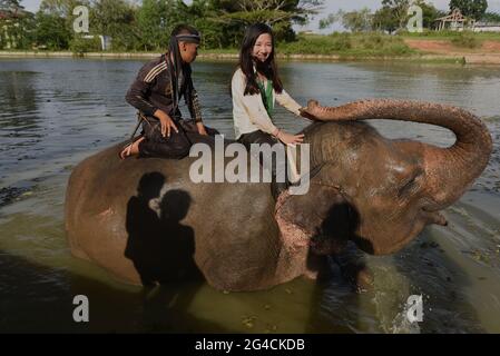 Ein Mahout und ein freiwilliger Arbeiter reiten auf einem Elefanten, nachdem er ihn im Sumatran Elephant Rehabilitation Center im Way Kambas National Park, Indonesien, gebadet hat. Stockfoto