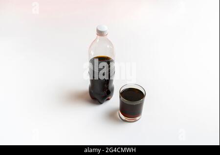 Schwarze Limonade in das Glas gegossen, Flasche Soda isoliert auf Farbhintergrund Stockfoto