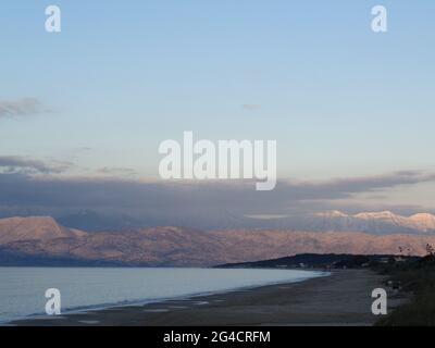 Flacher Sandstrand von Acharavi und Almiros, außerhalb der Saison, mit Bergen Albaniens, die über den Kanal von Korfu sichtbar sind Stockfoto