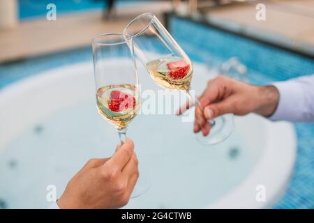 Sommerferien Konzeptbild. Zwei Glas kühlen Champagner Wein mit einem Teller Erdbeeren im Freien auf einer Pool-Terrasse in einem sonnigen Sommer Stockfoto