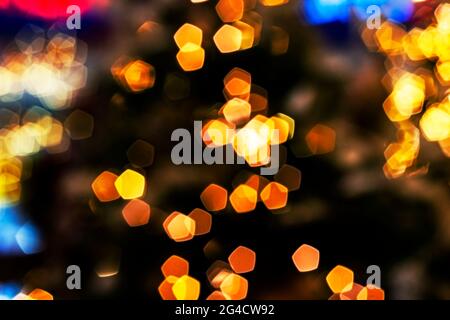 Verschwommenes goldenes Licht abstrakter Hintergrund in der Nacht, defokussierter dunkel leuchtender Bokeh Hintergrund, magisch gelb beleuchtetes Glitzermuster. Stockfoto