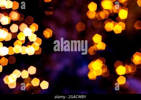 Verschwommenes goldenes Licht abstrakter Hintergrund in der Nacht, defokussierter dunkel leuchtender Bokeh Hintergrund, magisch gelb beleuchtetes Glitzermuster. Stockfoto