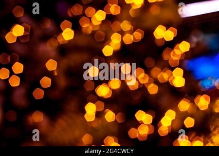 Verschwommenes goldenes Licht abstrakter Hintergrund in der Nacht, defokussierter dunkel leuchtender Bokeh Hintergrund, magisch gelb beleuchtetes Glitzermuster. Stockfoto