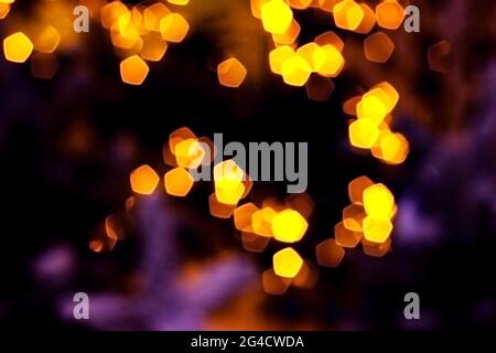 Verschwommenes goldenes Licht abstrakter Hintergrund in der Nacht, defokussierter dunkel leuchtender Bokeh Hintergrund, magisch gelb beleuchtetes Glitzermuster. Stockfoto