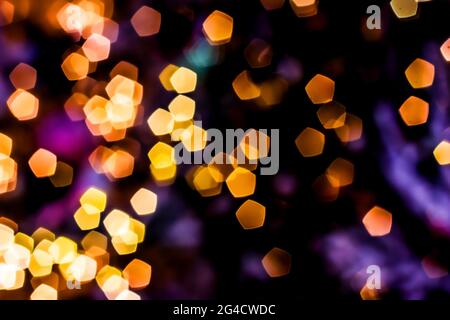 Verschwommenes goldenes Licht abstrakter Hintergrund in der Nacht, defokussierter dunkel leuchtender Bokeh Hintergrund, magisch gelb beleuchtetes Glitzermuster. Stockfoto