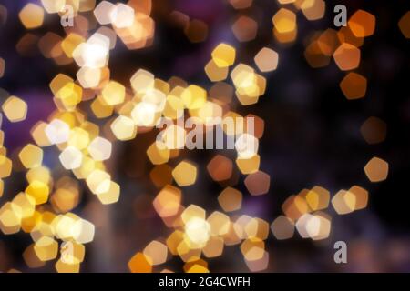 Verschwommenes goldenes Licht abstrakter Hintergrund in der Nacht, defokussierter dunkel leuchtender Bokeh Hintergrund, magisch gelb beleuchtetes Glitzermuster. Stockfoto