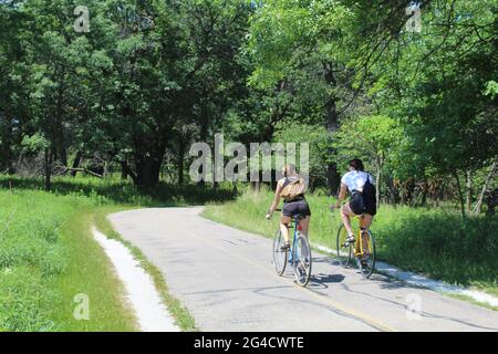 Zwei junge Frauen mit Rucksäcken fahren auf dem North Branch Trail in Miami Woods in Morton Grove, Illinois Stockfoto