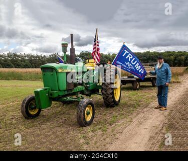 Landwirt John mit seinem John Deere 3020 Traktor, der ein Trump-Banner und auch eine amerikanische Flagge auf dem Traktor aushält. Stockfoto