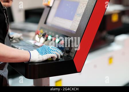 Arbeiter an den Steuerungen der Laserschneidmaschine. Selektiver Fokus. Stockfoto