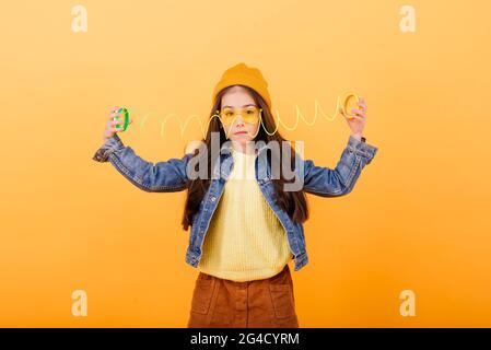 Ein Mädchen in einem mehrfarbigen Hemd hält ein mehrfarbiges, slinky Spielzeug In ihren Händen Stockfoto