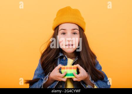 Ein Mädchen in einem mehrfarbigen Hemd hält ein mehrfarbiges, slinky Spielzeug In ihren Händen Stockfoto