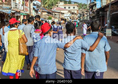 Rückansicht von drei indischen Schuljungen mit Armen auf den Schultern, die die Straße hinunter gingen, Gokarna, Karnataka, Indien Stockfoto