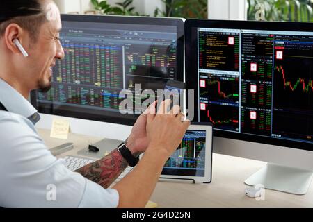 Positive Trader analysieren Börsendaten auf Bildschirmen von Computer, digitalem Tablet und Smartphone gleichzeitig Stockfoto