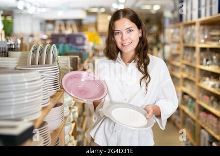 Junge Frau, die im Laden neue Gerichte auswählt Stockfoto