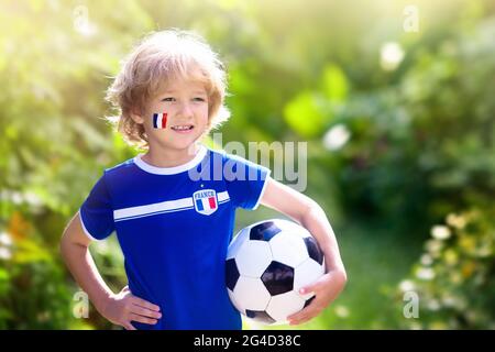 Kinder spielen Fußball auf dem Außenplatz. Fans der französischen Nationalmannschaft. Kinder erzielen ein Tor beim Fußballspiel. Kleiner Junge in französischem Trikot und Stollen tritt den Ball. Stockfoto