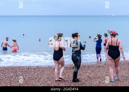 Brighton & Hove, Großbritannien. 21. JUNI 2021 Sonnenwendschwimmer, Mitglieder der salzigen Seevögel-Gruppe, tragen Blumenkronen und betreten das Wasser, um den längsten Tag bei Sonnenaufgang unter bewölktem Himmel zu feiern. Wetter in Großbritannien. Foto ©Julia Claxton Credit: Julia Claxton/Alamy Live News Stockfoto