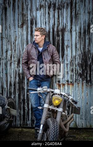 Mann in Jeans und Lederjacke mit individualisiertem Cafe Racer Motorrad Stockfoto