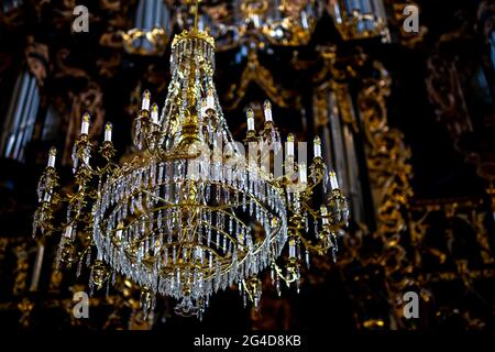 Schöner Kristallleuchter in der Kirche. Im Hintergrund ein verschwommenes, reich verzierte Gewölbe. Aufnahme bei natürlichem, weichem Licht. Schlechte Beleuchtung Stockfoto