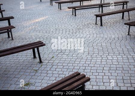 Viele Bänke in einem mit Granit gepflasterten Platz. Aufnahme bei natürlichem, weichem Licht. Ein leicht schattiger Ort. Stockfoto