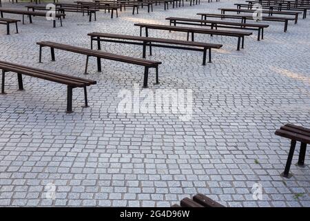 Viele Bänke in einem mit Granit gepflasterten Platz. Aufnahme bei natürlichem, weichem Licht. Ein leicht schattiger Ort. Stockfoto