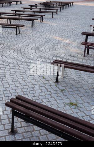 Viele Bänke in einem mit Granit gepflasterten Platz. Aufnahme bei natürlichem, weichem Licht. Ein leicht schattiger Ort. Stockfoto