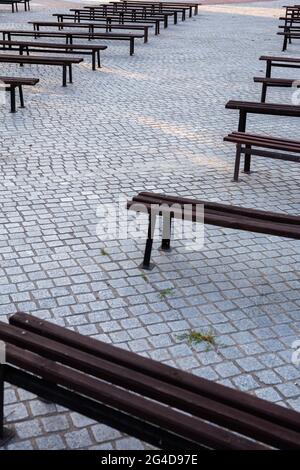 Viele Bänke in einem mit Granit gepflasterten Platz. Aufnahme bei natürlichem, weichem Licht. Ein leicht schattiger Ort. Stockfoto