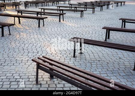 Viele Bänke in einem mit Granit gepflasterten Platz. Aufnahme bei natürlichem, weichem Licht. Ein leicht schattiger Ort. Stockfoto