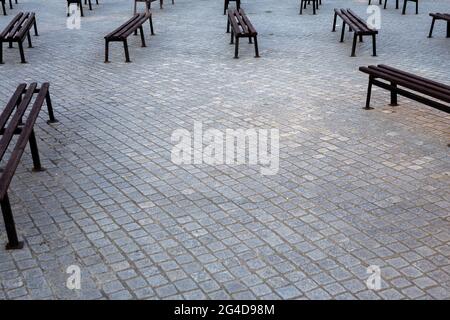 Viele Bänke in einem mit Granit gepflasterten Platz. Aufnahme bei natürlichem, weichem Licht. Ein leicht schattiger Ort. Stockfoto