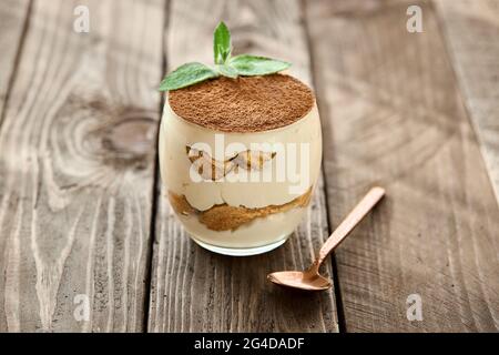 Klassisches Dessert Tiramisu in einem Glas auf einem Holzbrett an einem sonnigen Tag. Stockfoto