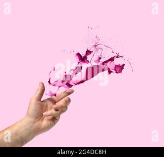 Kreativität Konzept Hand werfen Licht magenta Farbe spritzt auf rosa Hintergrund Stockfoto