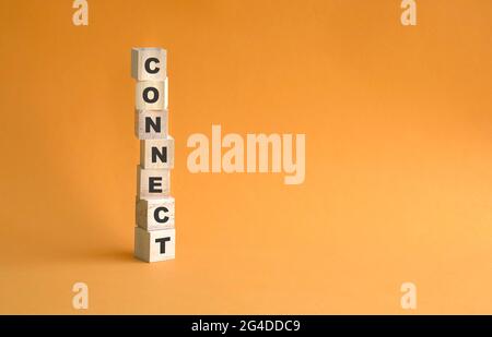 Word Connect auf Holzwürfel gestapelt geschrieben. Orangefarbener Hintergrund, Kopierbereich. Stockfoto