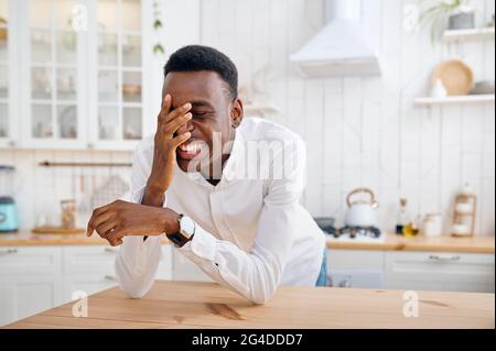 Lachender Mann, der an der Theke in der Küche sitzt Stockfoto