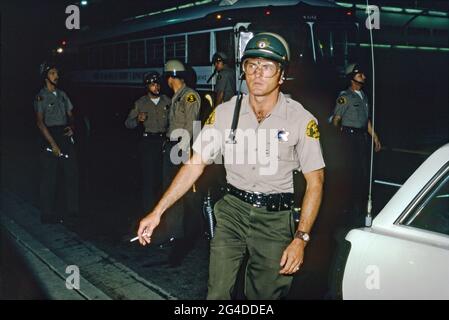 Die Polizei ist bei den Straßenmärschen und Paraden anwesend, die sich am Unabhängigkeitstag (Día de la Independencia) der Gemeinde Chicano in Los Angeles, Kalifornien, USA, 1970, drehten. Neben der Feier ihrer kulturellen Identität, wie auch mit anderen Minderheiten in den USA, wurden Themen rund um den Krieg in Vietnam, Gleichheit, Armut, Arbeitsmöglichkeiten, Behörden und Polizei ausgestrahlt. Vor ihrem Bus tragen Mitglieder des Sheriffs-Departements des County of Los Angeles Helme, Waffen und Schlagstöcke. Dieses Bild aus dem 17. Jahrhundert stammt aus einer Transparenz, die von einem Amateurfotografen aufgenommen wurde. Stockfoto