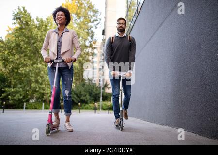 Junges Paar im Urlaub, das Spaß hat, mit dem Elektroscooter durch die Stadt zu fahren. Stockfoto