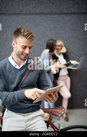 Gruppe von Geschäftsleuten, die elektronische Geräte im Freien verwenden Stockfoto
