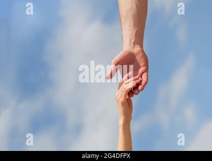 Eine helfende Hand geben. Hände von Mann und Frau auf blauem Himmel Hintergrund. Eine helfende Hand geben. Solidarität, Mitgefühl und Nächstenliebe, Rettung Stockfoto