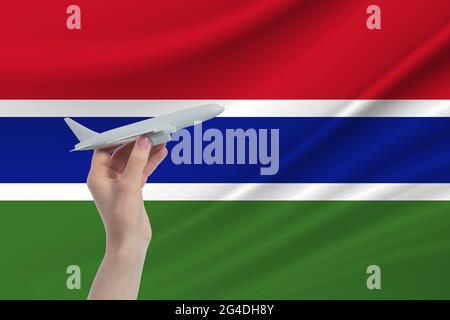 Flugzeug in der Hand mit der Nationalflagge von Gambia. Reise nach Gambia. Stockfoto