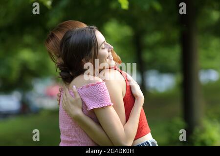Zwei glückliche Frauen umarmen sich und treffen sich in einem grünen Park Stockfoto