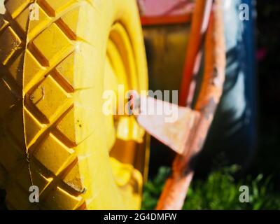 Selektive Nahaufnahme auf das Profil des gelben Gummirades des Gartenwagens, das von hellem Sonnenlicht auf unscharfem Hintergrund beleuchtet wird Stockfoto